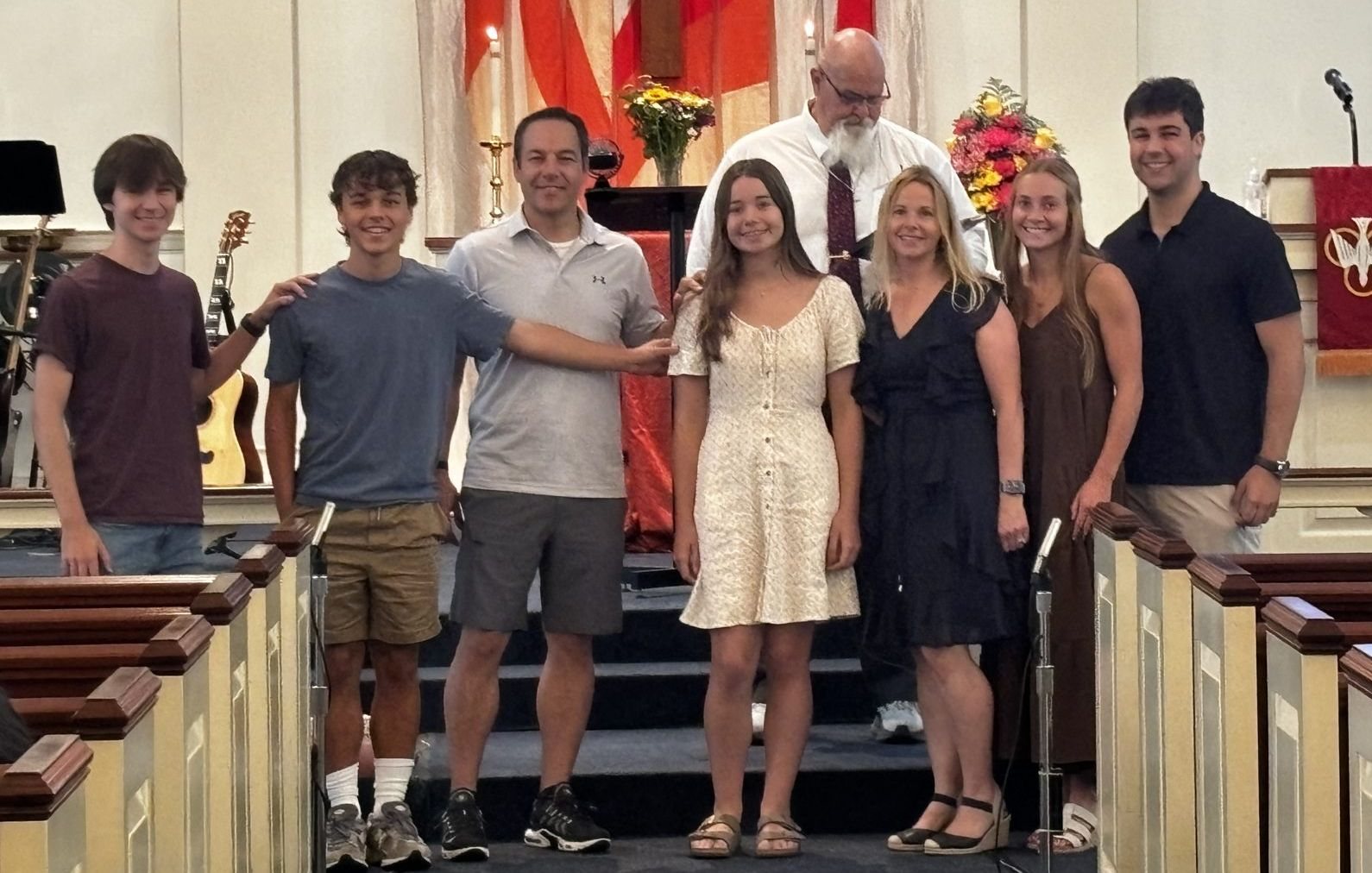The Carlisle family standing at the front of a church sanctuary with the pastor